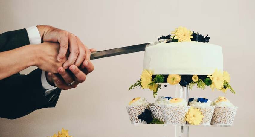 two pairs of hands cutting a wedding cake