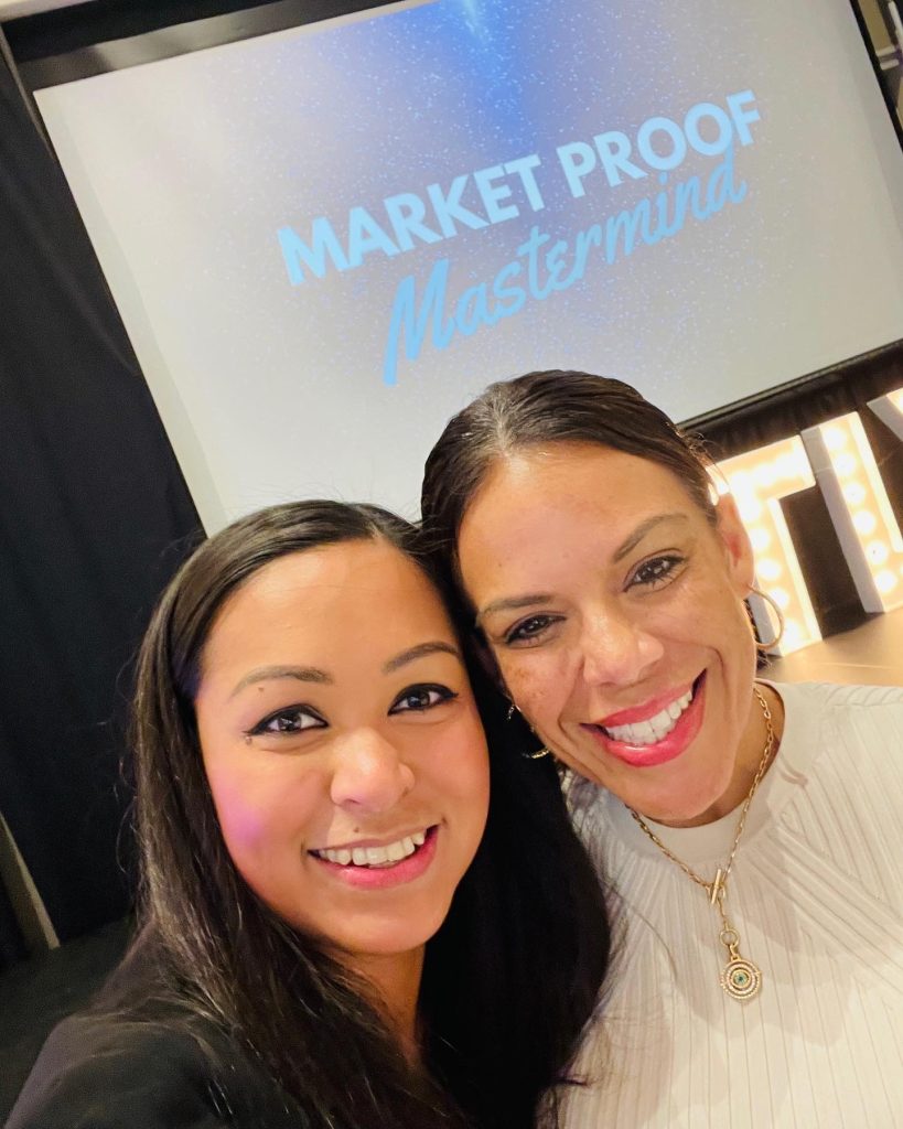 Attendees posing in front of Market Proof Mastermind stage at a corporate event