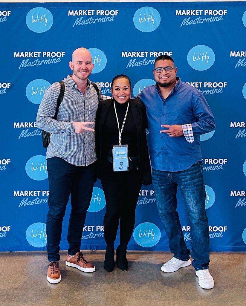 Attendees posing in front of branded Market Proof Mastermind backdrop